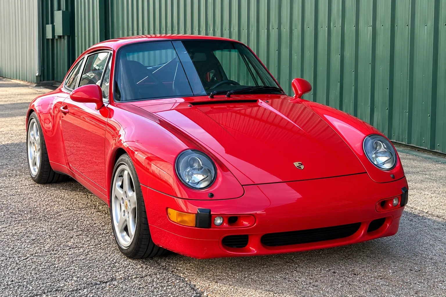 Red classic Porsche with installed windshield outside the workshop.